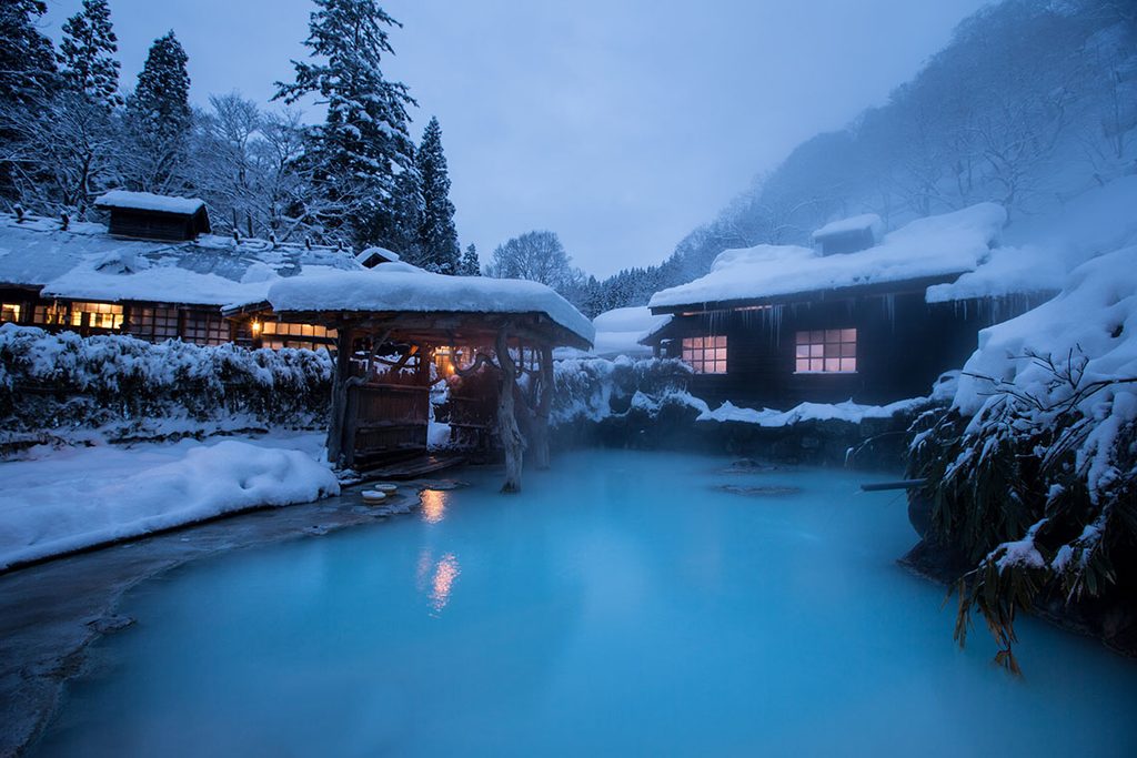 雪景色に包まれた鶴の湯温泉の乳白色の露天風呂
